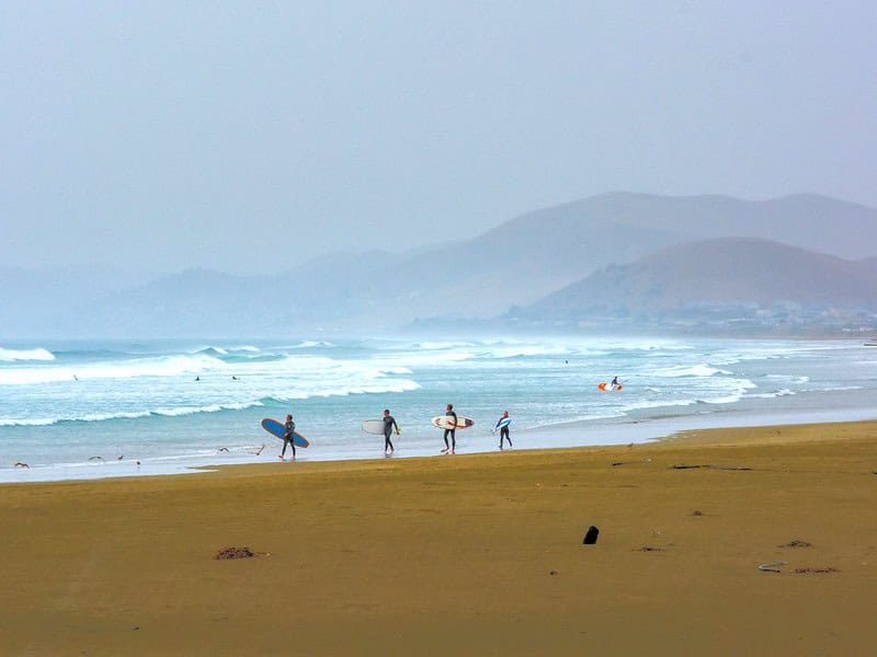 Surfers walking at Morro Rock beach