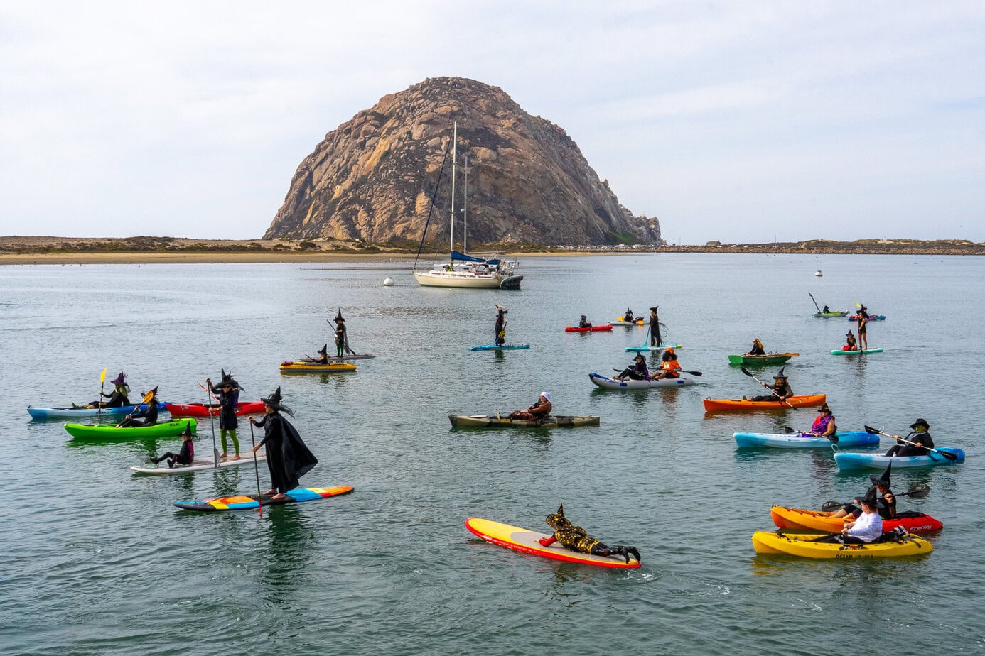 Witches and warlocks paddling across Morro Bay with Morro Rock in the background