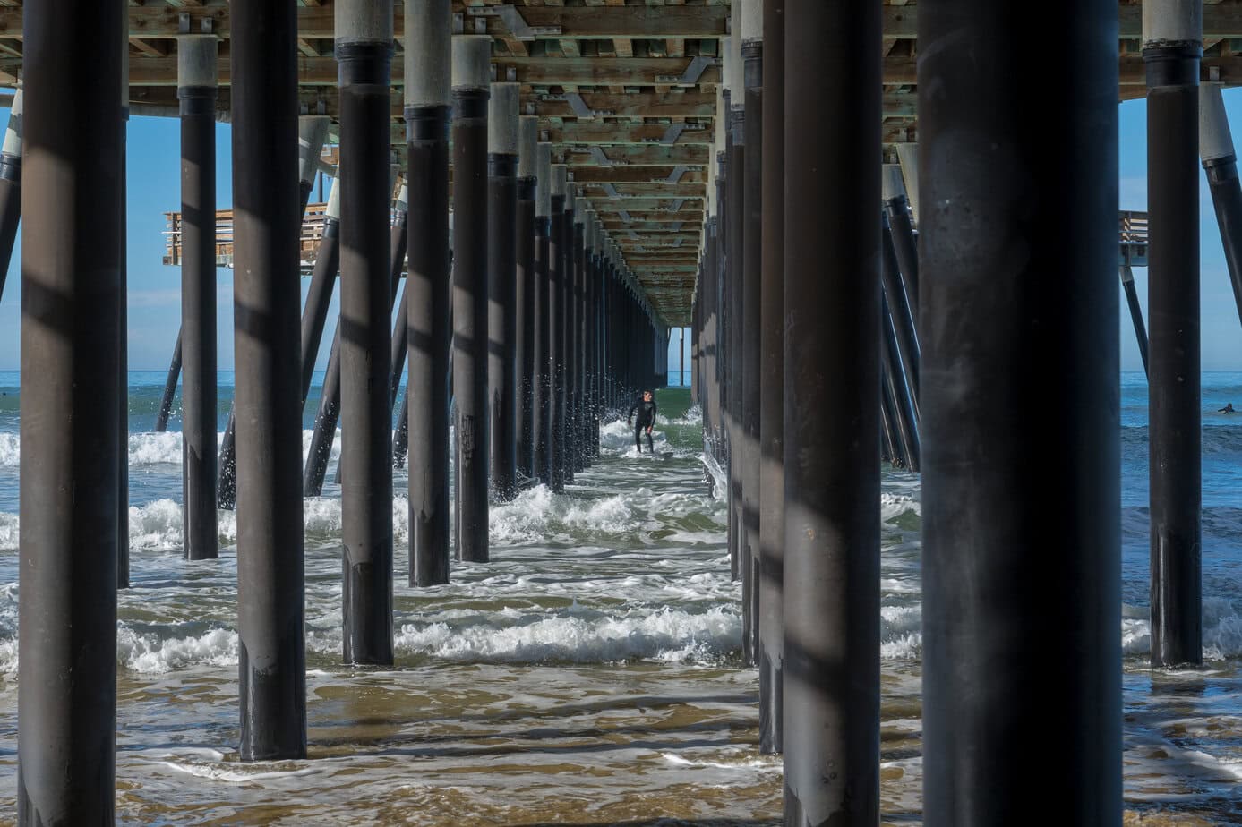 Symmetrical view through the structure of Pismo Beach Pier with waves flowing underneath