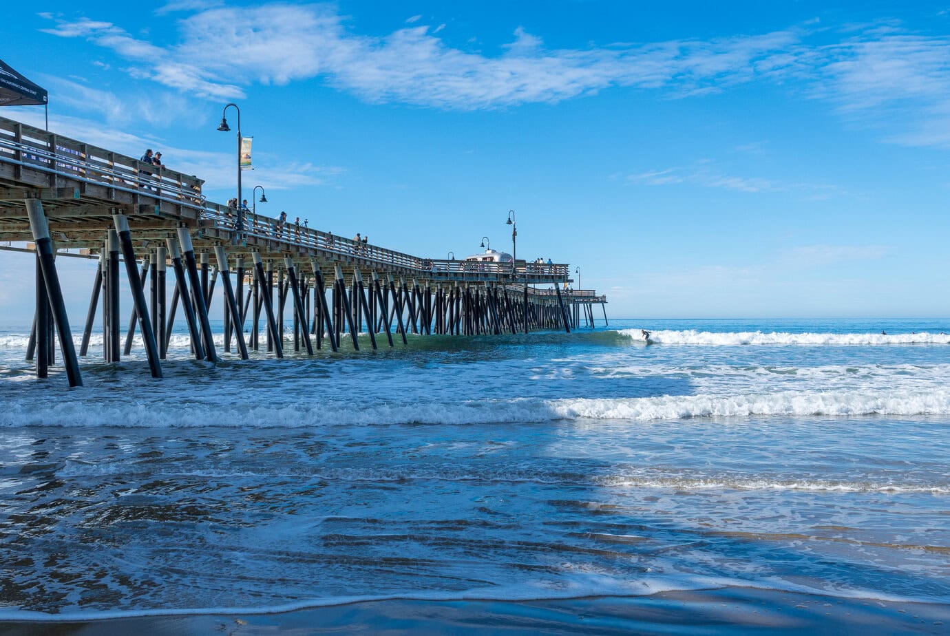 Pismo Beach Pier with a surfer riding a wave along the California Central Coast