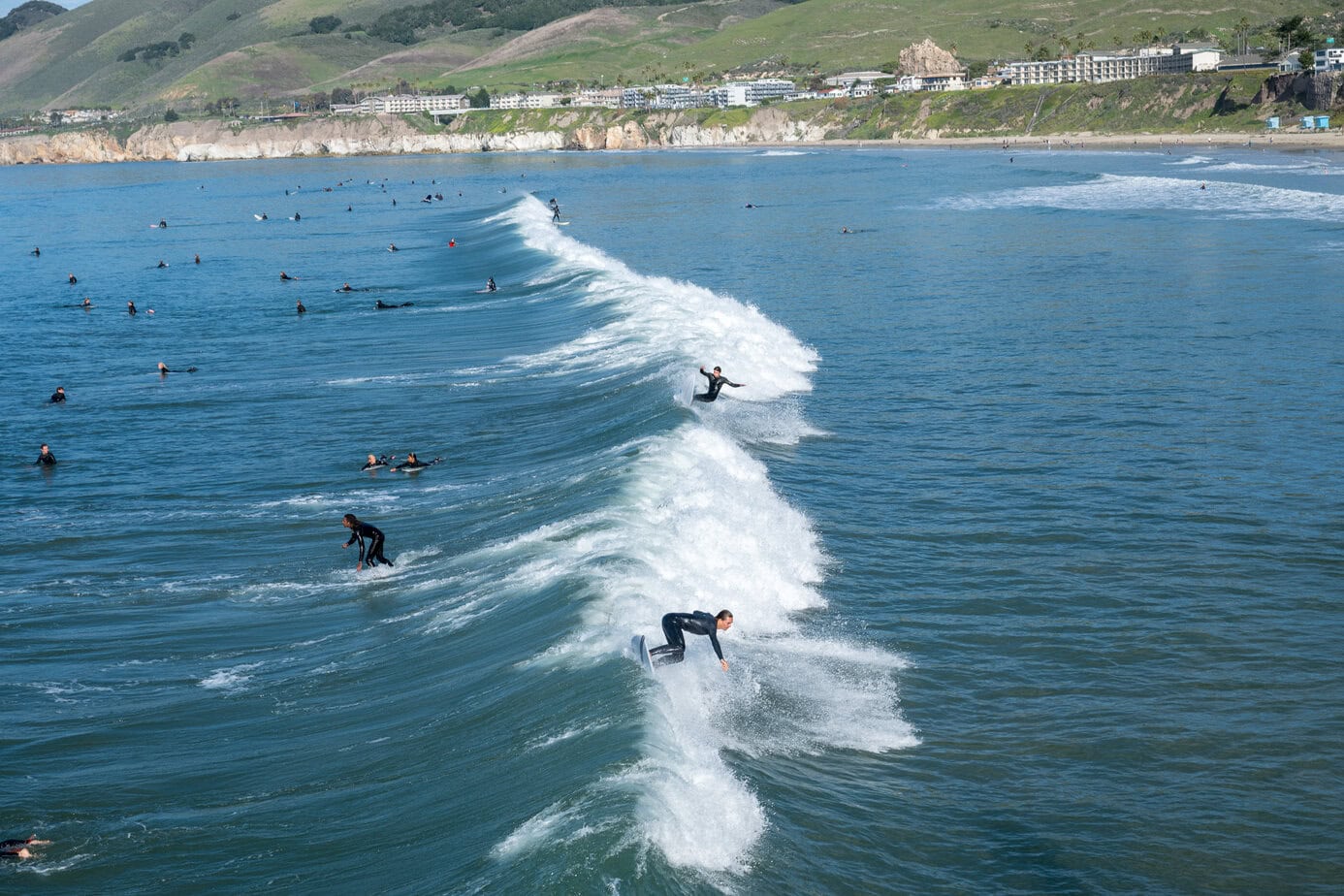 Surfers riding waves near Pismo Beach Pier along the Central Coast