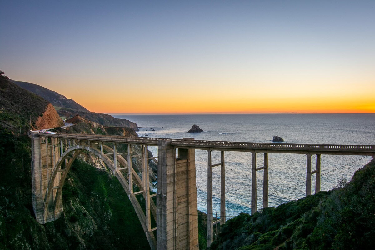 Bixby Creek Bridge at sunset along Highway 1 in Big Sur, with coastal cliffs and the Pacific Ocean below