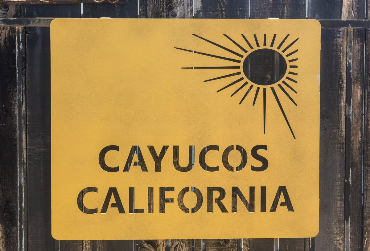 Yellow Cayucos California sign with a simple sun design in downtown Cayucos.