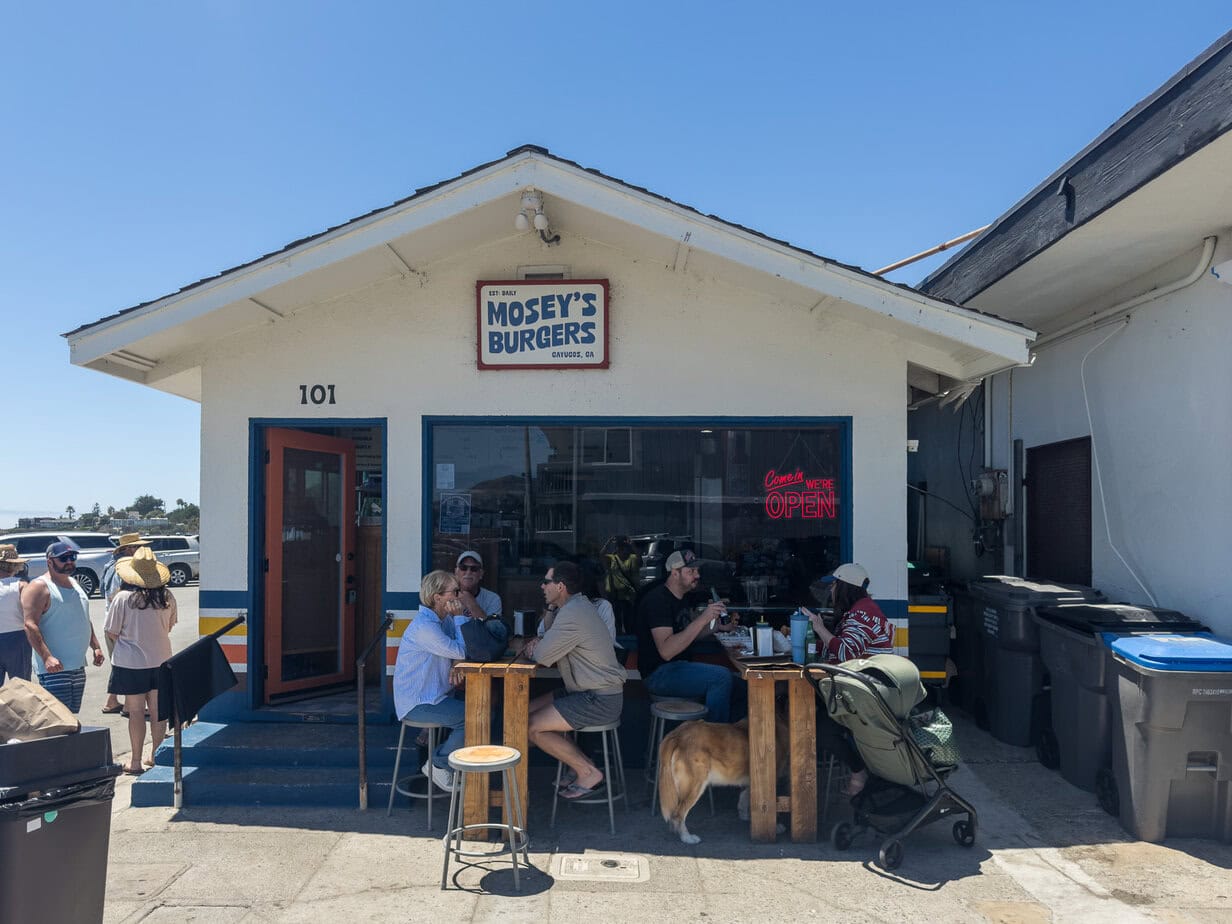 Mosey's Burgers on D Street in Cayucos with diners seated outside the small burger shop.
